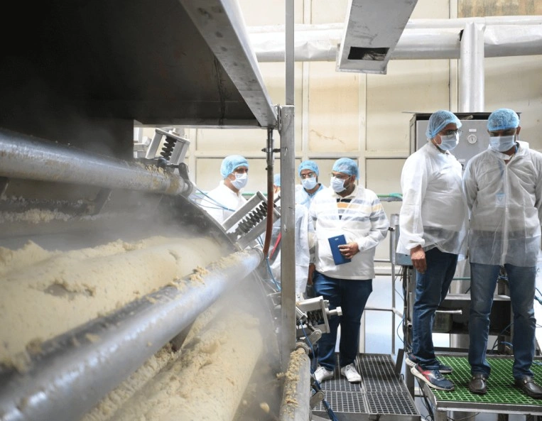 A group of people gathered around a machine, observing and discussing its functions and features.