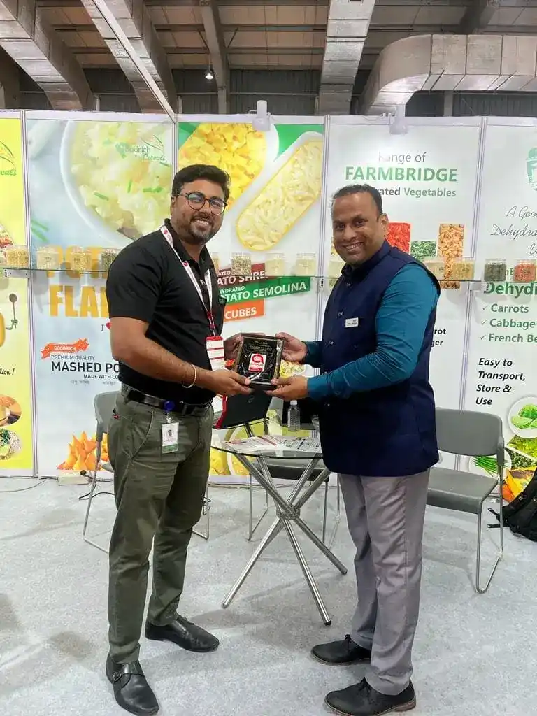 Two men at Goodrich exhibition in Anuga Mumbai, standing together, possibly receiving an award.