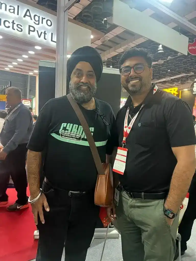 Two men smiling and posing for a photo at the Goodrich exhibition Anuga Mumbai event.