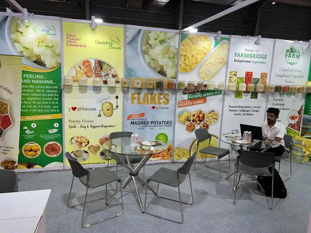 A man sitting at a table in front of a large display at the Goodrich exhibition Anuga Mumbai.