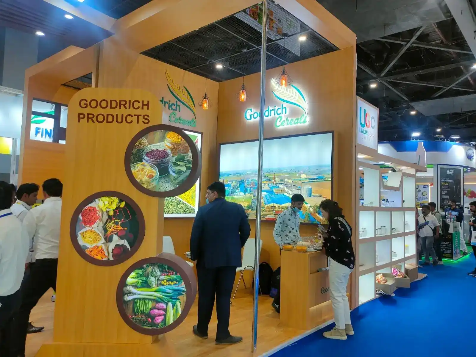 A group of people gathered around a booth at the Goodrich exhibition Aahar India, with a sign displaying Goodrich products.